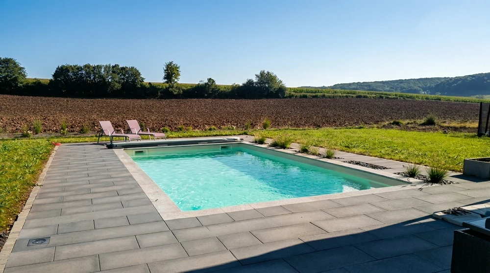 Piscine rectangulaire extérieure avec dallage en béton gris anthracite, eau turquoise claire