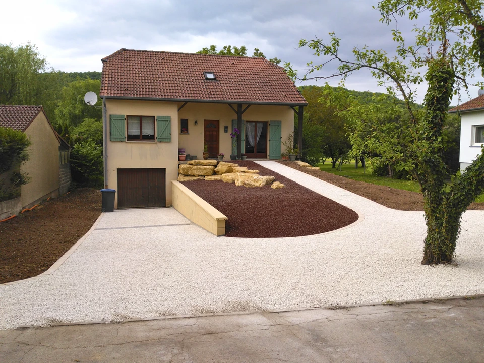 Jardin paysager extérieur avec allée courbe en dalles de grès rose disposées en quinconce sur pelouse verte entretenue