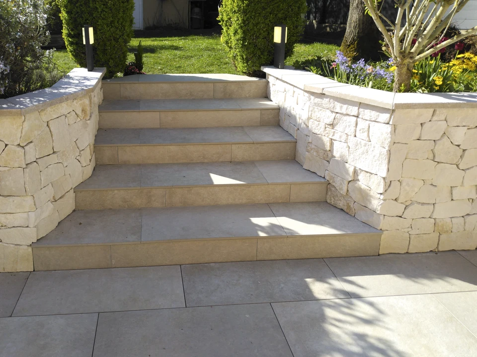 Escalier extérieur en pierre naturelle serpentant dans un jardin paysager en pente