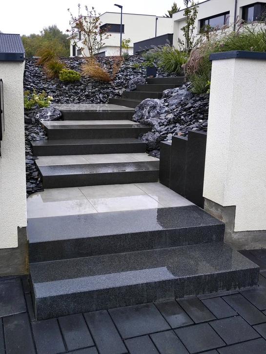 Terrasse extérieure pavée en pavés autobloquants béton bicolores gris anthracite et gris clair, pose en calepinage décalé